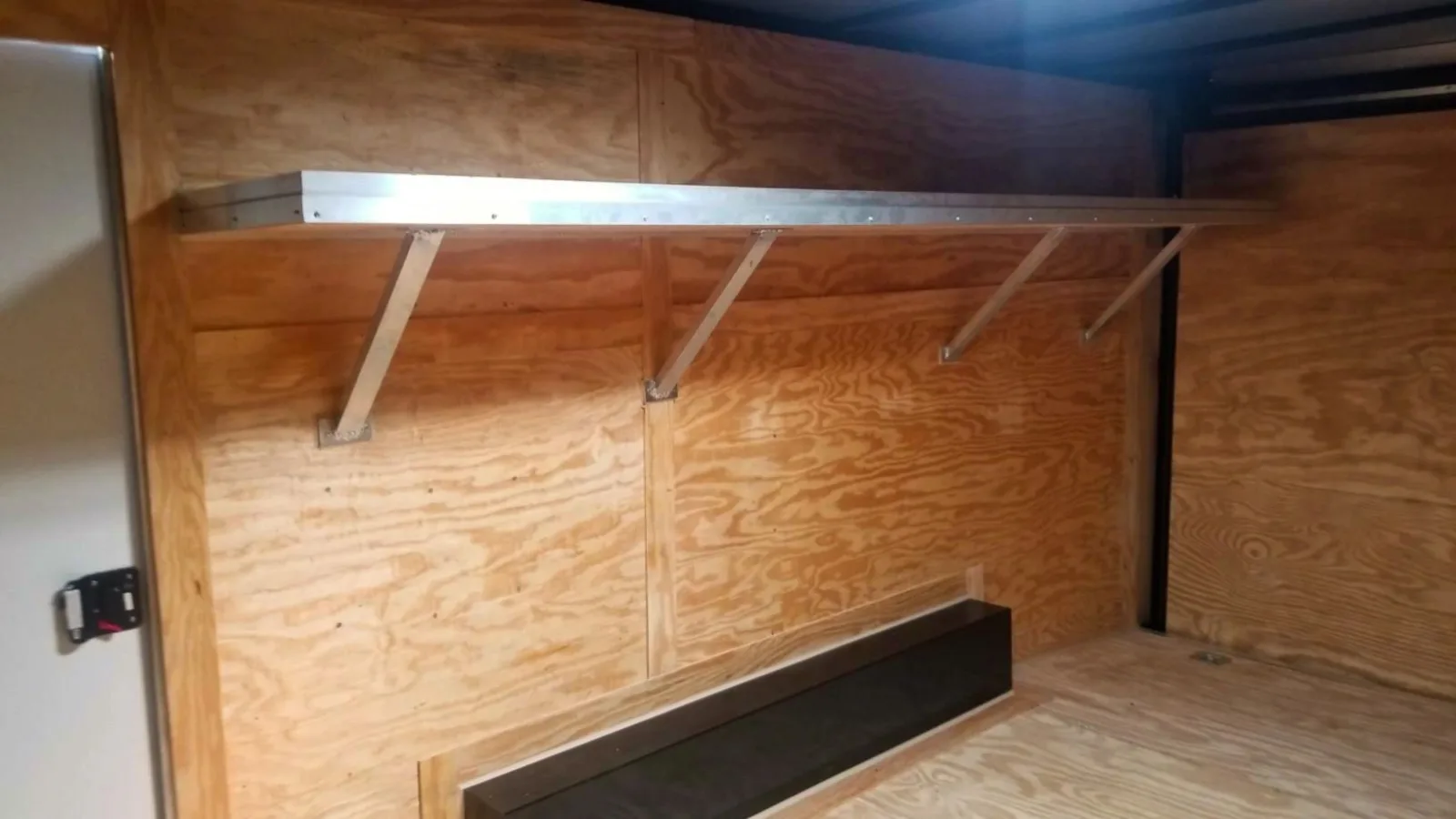 Aluminum wall shelf mounted inside an enclosed cargo trailer